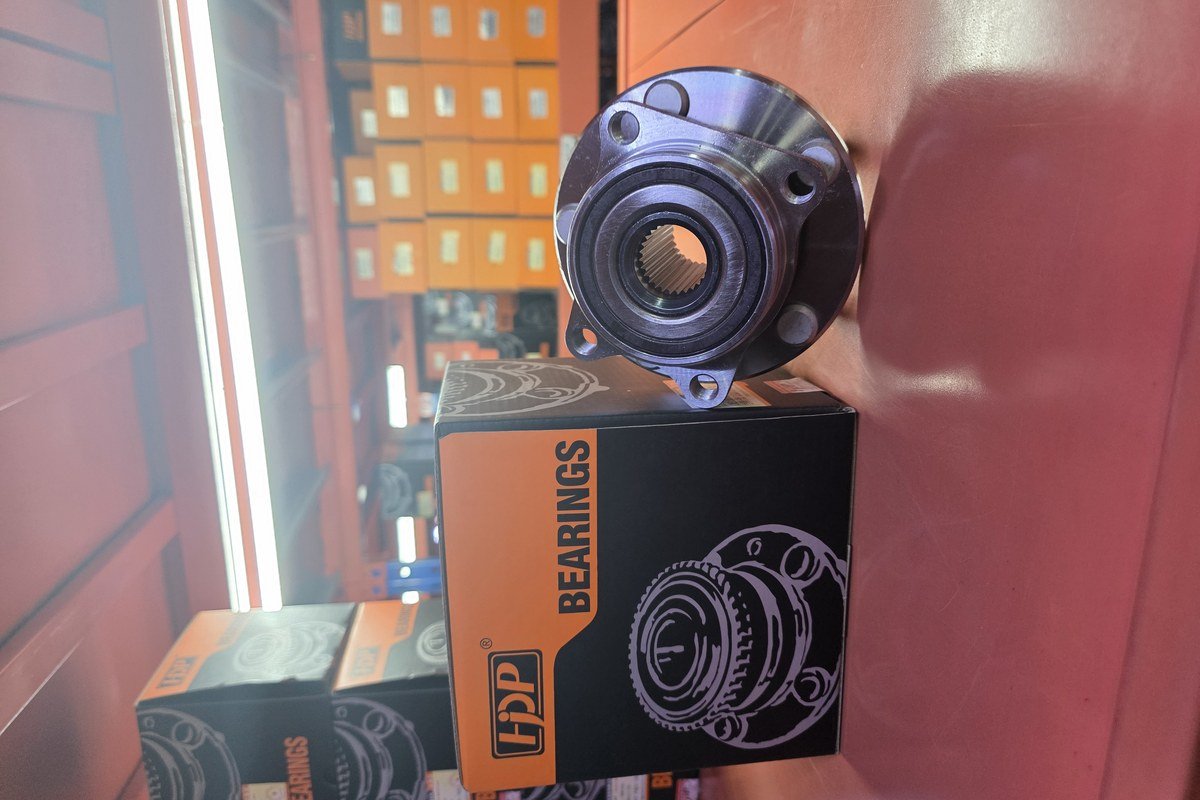 Gloved hands torquing a wheel hub mounting bolt on a stripped front knuckle in a workshop
